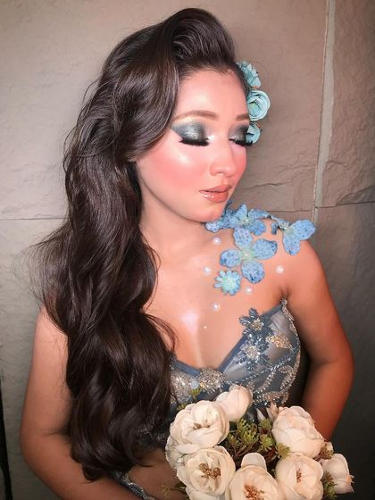 A close-up of the 'Frosty Vibes' look, showcasing the beautiful blue eyeshadow and the delicate floral details on the shoulder and in the hair.