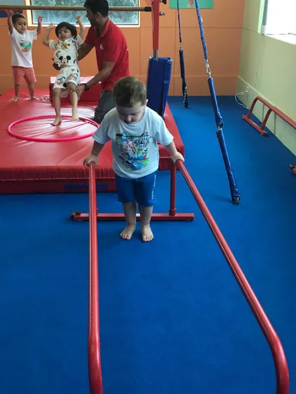 This preschooler carefully navigates a low set of parallel bars, an activity designed for this age group to build confidence and coordination.