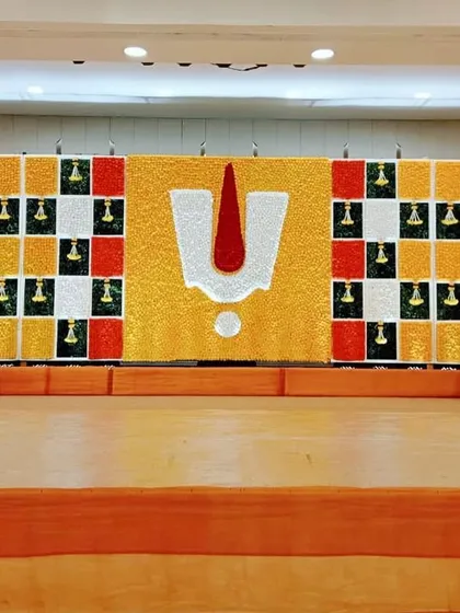 A unique and colorful stage we designed for a Janoi ceremony. The backdrop is made entirely of flowers, creating a vibrant mosaic with a central 'tilak' symbol, showcasing a creative and modern take on traditional motifs.