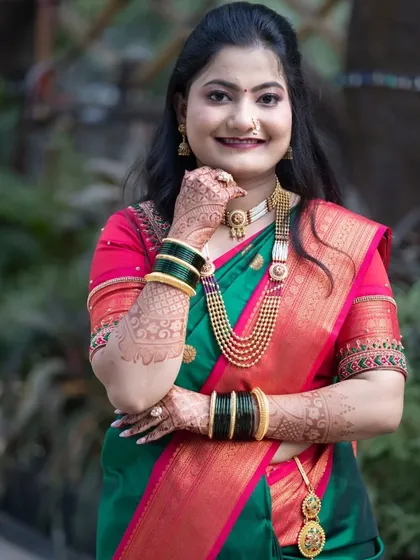 A close-up portrait of a Marathi bride, highlighting her traditional jewelry, green glass bangles, and intricate mehndi.