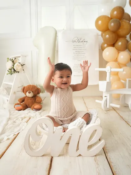 Hands up if you're one. This joyful shot captures the pure excitement of a first birthday celebration.
