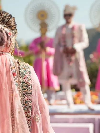 The bride's view. An artistic shot taken from behind the bride as she looks towards her groom during their daytime Varmala ceremony.