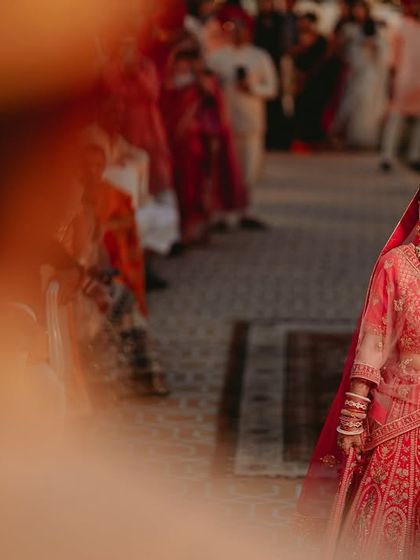 An artistic shot of the bride walking down the aisle, framed by a blurred foreground to draw focus to her happy expression.