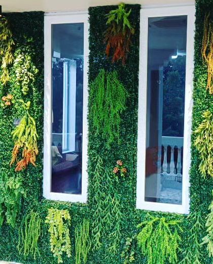 This exterior wall installation shows how I can frame windows with different types of hanging artificial plants. The mix of green, yellow, and orange foliage creates a dynamic and natural look.