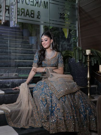 A full-length shot of this glamorous look. The heavily embellished teal lehenga is perfectly balanced by the bold makeup and sleek hair.