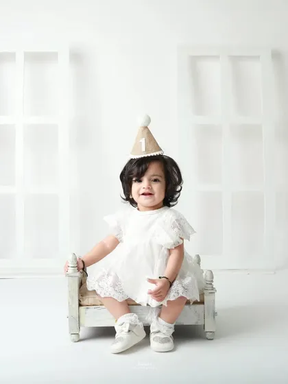 Sitting pretty on a miniature bed, this little girl is the perfect picture of a one-year-old princess.