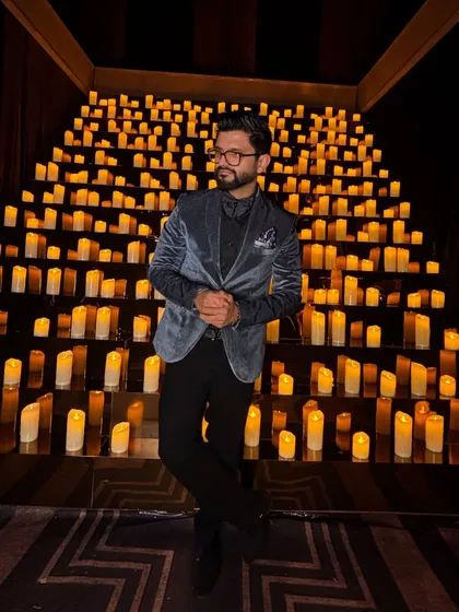 A classic formal look with a velvet blazer, standing in front of a stunning candle-lit backdrop.