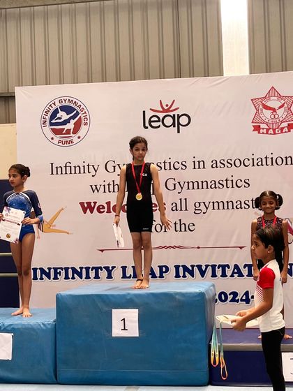 A young athlete receives her medal at the Infinity Leap Invitational. Each medal represents a milestone in her gymnastics journey.