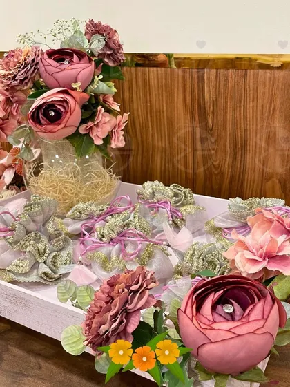 A tray of beautifully wrapped return favors for a wedding. The dusty rose and gold color palette, combined with delicate floral arrangements, creates a sophisticated and cohesive look.