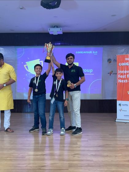 A gold medal-winning team from the elementary category at Codeavour 6.0 Nationals holds their trophy high with their proud mentor.