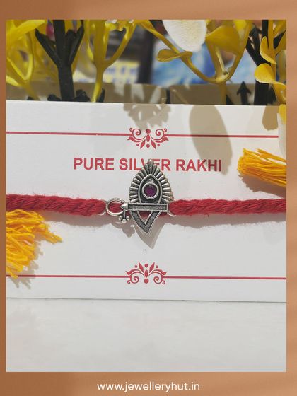 A beautiful and artistic pure silver Rakhi with a single red stone, combining tradition with elegant design.