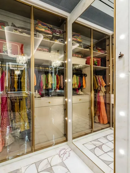 A close-up of the glass-fronted cabinets, which beautifully display a collection of traditional Indian wear. The integrated lighting ensures every item is perfectly illuminated.