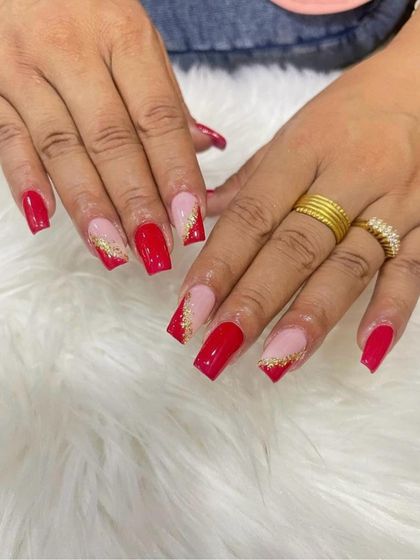 A bold and festive set of red, square-shaped extensions with a gold glitter French tip accent.