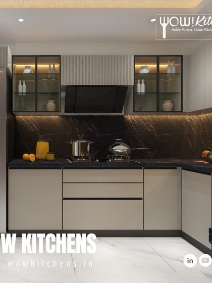 The L-shaped layout of this kitchen provides an efficient workspace, with the stainless steel refrigerator perfectly complementing the beige and black color scheme.
