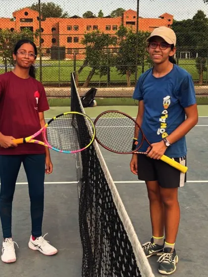 Two of our players posing at the net after a competitive match. We encourage healthy competition and sportsmanship among all our students.