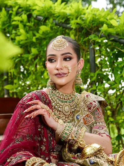 A regal pose capturing the intricate details of the bridal jewelry and the perfectly sculpted makeup. The defined eyes and glowing skin create a look of pure elegance.