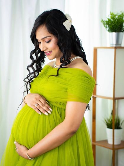 A beautiful close-up of a mom-to-be in a bright lime green gown. The shot focuses on her gentle expression and the lovely details of her hair and makeup.