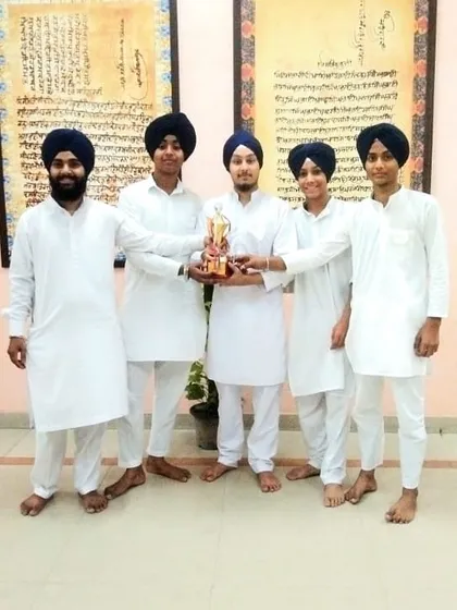 Our proud students holding their first prize trophy from a recent kirtan competition. We encourage participation in competitions to build experience, discipline, and a spirit of excellence.