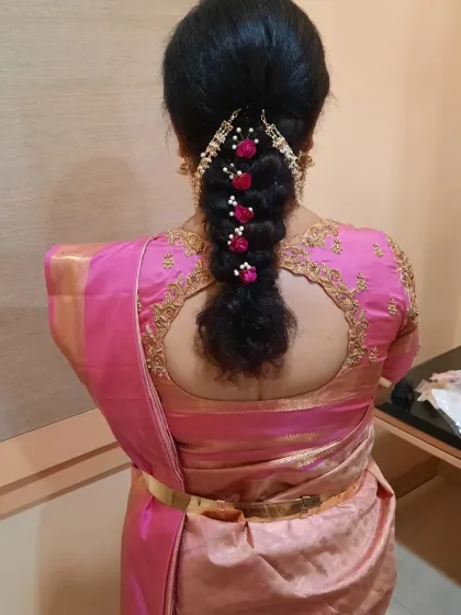 A beautiful bridal braid for a Varapooja ceremony, decorated with delicate pink and white artificial flowers. This is a great option for adding a touch of color to the hairstyle.