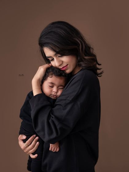 A mother holding her sleeping baby close.
