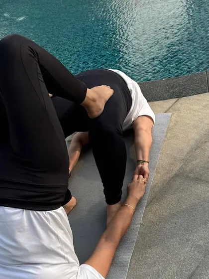 A partner inversion by the pool, combining a shoulder stand with a supportive base. This advanced work is built on a foundation of trust and clear communication.
