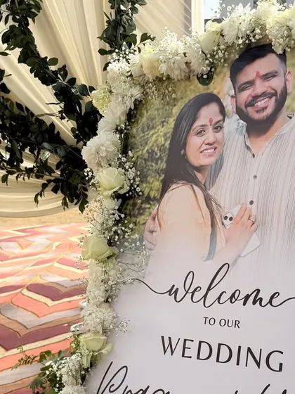 A personalized welcome sign for Pragya & Yash's wedding, framed with white flowers and set at the beginning of the beautifully decorated entrance path.