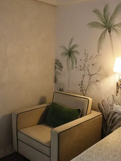 This view shows how the nature-inspired wallpaper seamlessly integrates with the room's furnishings, creating a cohesive and tranquil corner for rest and relaxation.