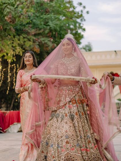 The bride's grand entrance, with her veil held aloft as she walks through the palace courtyard, creating a classic and beautiful bridal moment.