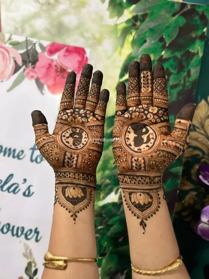 This design features a silhouette of a pregnant woman and a baby in a cradle, surrounded by traditional mehendi patterns. The lotus at the wrist adds a touch of elegance.