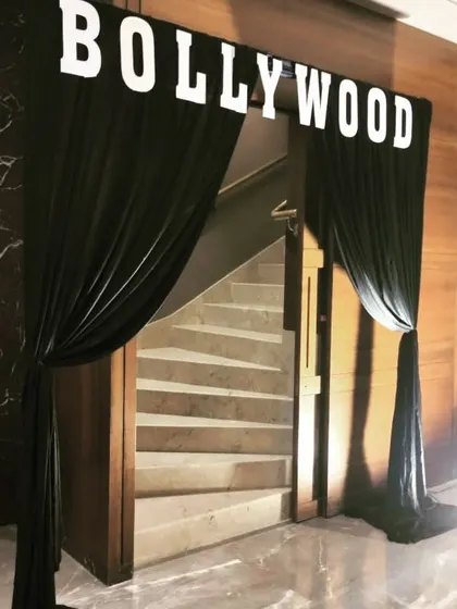 Setting the stage for a corporate 'Bollywood Bash'. The grand entrance with black drapes and bold lettering immediately immerses guests in the glamorous theme of the evening.