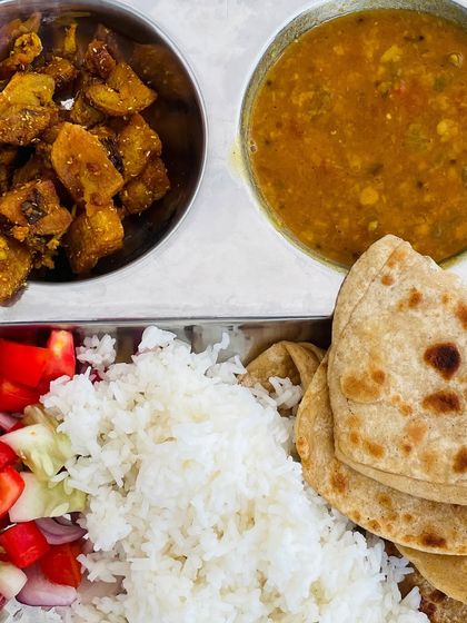 A simple and satisfying meal of paratha and rice. It is served with a dry vegetable dish, our classic dal, and a fresh cucumber and tomato salad.