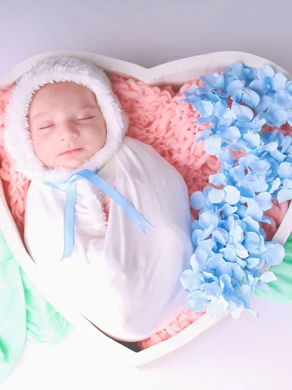A beautiful overhead shot of the baby sleeping in the heart bowl, surrounded by soft blue flowers.