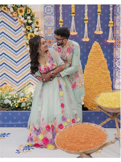 A happy couple shares a moment during their Moroccan-themed Haldi, surrounded by colorful decor and bowls of turmeric.