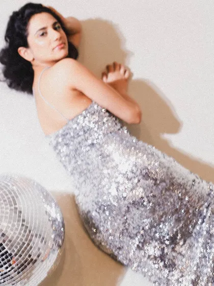 A glamorous shot from a 30th birthday shoot, with the subject lying next to a disco ball in a sequined dress.