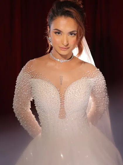 The full bridal look, ready for the aisle. The pearl-studded gown is complemented by a soft, romantic makeup look that makes her look like a princess.