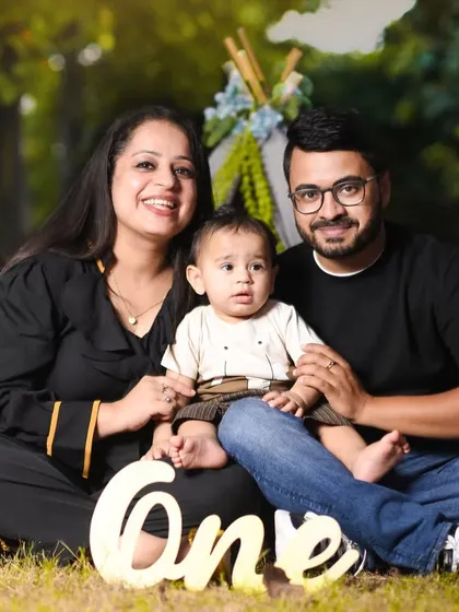 A lovely family photo taken during an outdoor first birthday shoot, with their little one sitting happily between them in front of our teepee setup.