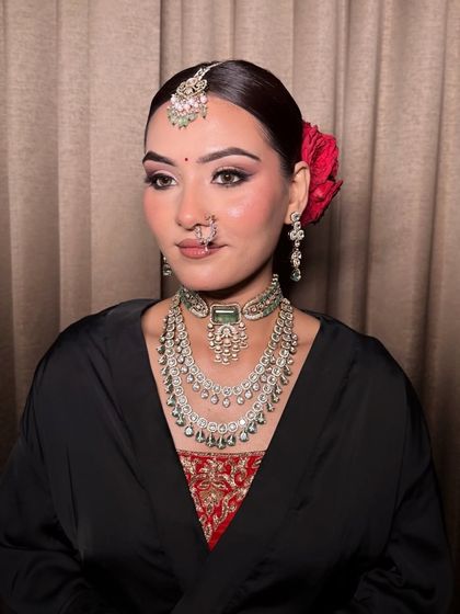 This elegant bridal look features a sleek bun with a fresh rose, complementing the soft smokey eye and glowing skin.