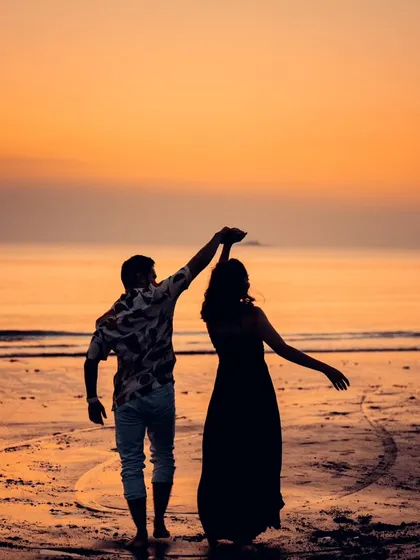 A beautiful silhouette of a couple dancing on a Mumbai beach at sunset. The vibrant sky and romantic pose make this a classic and stunning pre-wedding photograph.