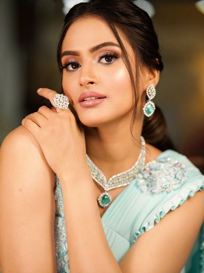 A close-up on the jewelry and makeup, showing how the tones of the makeup complement the emeralds in her necklace.