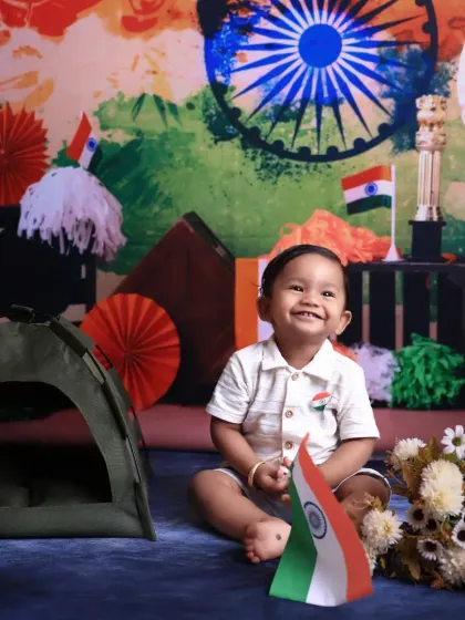 The joyful spirit of a child celebrating Independence Day. A smiling baby sits surrounded by tricolor decorations, holding a small Indian flag, capturing a moment of pure, patriotic happiness in our studio.