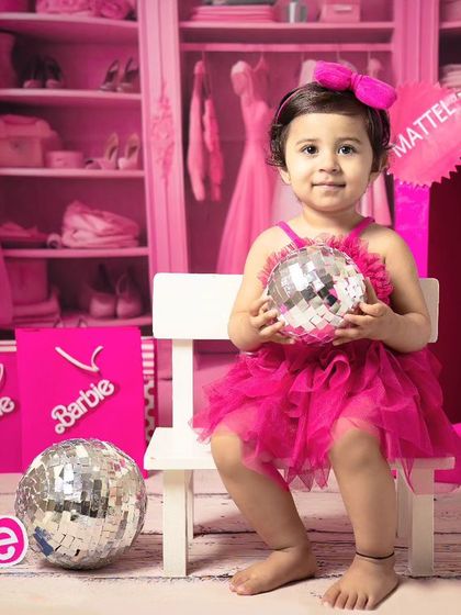 A little girl holds a disco ball during her second birthday Barbie-themed shoot, showing off a fun and playful side.