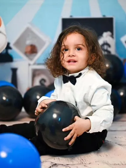 Another little one enjoying our Boss Baby setup. The decor uses a consistent color scheme of blue, black, and white, with plenty of balloons for the child to interact with.