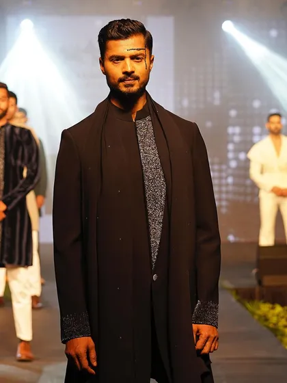 A dramatic moment on the runway, with lighting that accentuates the texture and silhouette of the outfit.