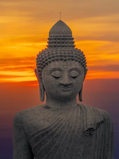 A close-up shot of the Big Buddha statue in Phuket against a fiery sunset, celebrating the peace and wisdom of Gautam Buddha on Buddha Poornima.