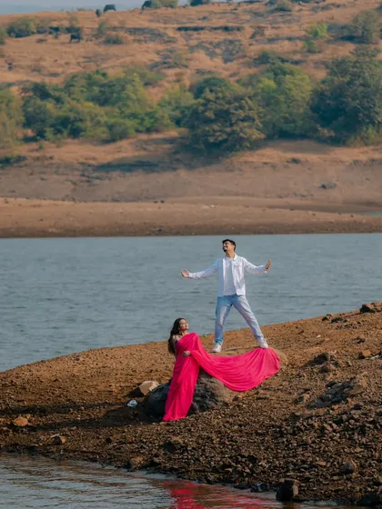 For the couple that dreams in Bollywood, we bring the silver screen to life. This dramatic, 'gerua' inspired shot by the lake captures the grand romance and vibrant color of a filmy love story.