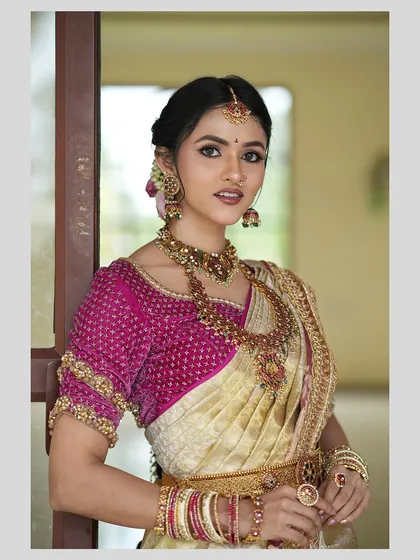 A closer look at the magenta bridal blouse, featuring intricate beadwork and embroidery. The detailed craftsmanship on the sleeves adds a layer of regal texture to the classic silk saree ensemble.