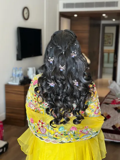 A close-up of the butterfly and pearl accessories in the curly hair.