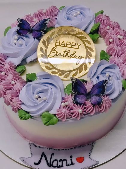A beautiful floral cake for Nani's birthday. This Belgian chocolate cake is adorned with a wreath of purple roses and delicate butterflies.