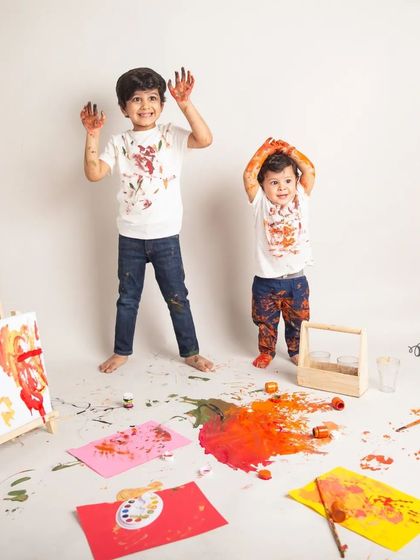 Hands up if you're having fun. The two brothers show off their paint-covered hands during a messy but memorable color splash photoshoot in the studio.