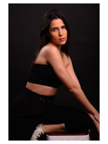 A minimalist and modern fashion portrait. The simple black outfit and dark background create a sleek and sophisticated look.